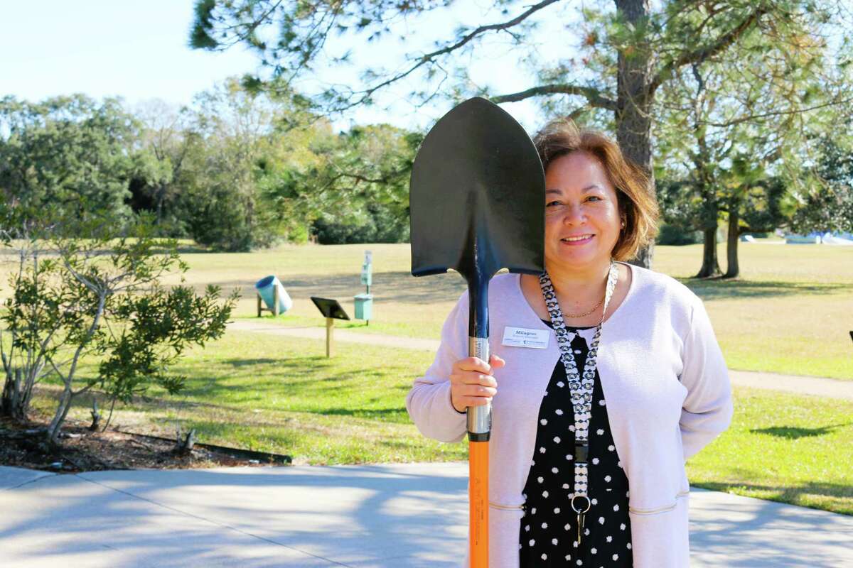 Milagros Tanega, librarian standing outside on a sunny day, holding a shovel